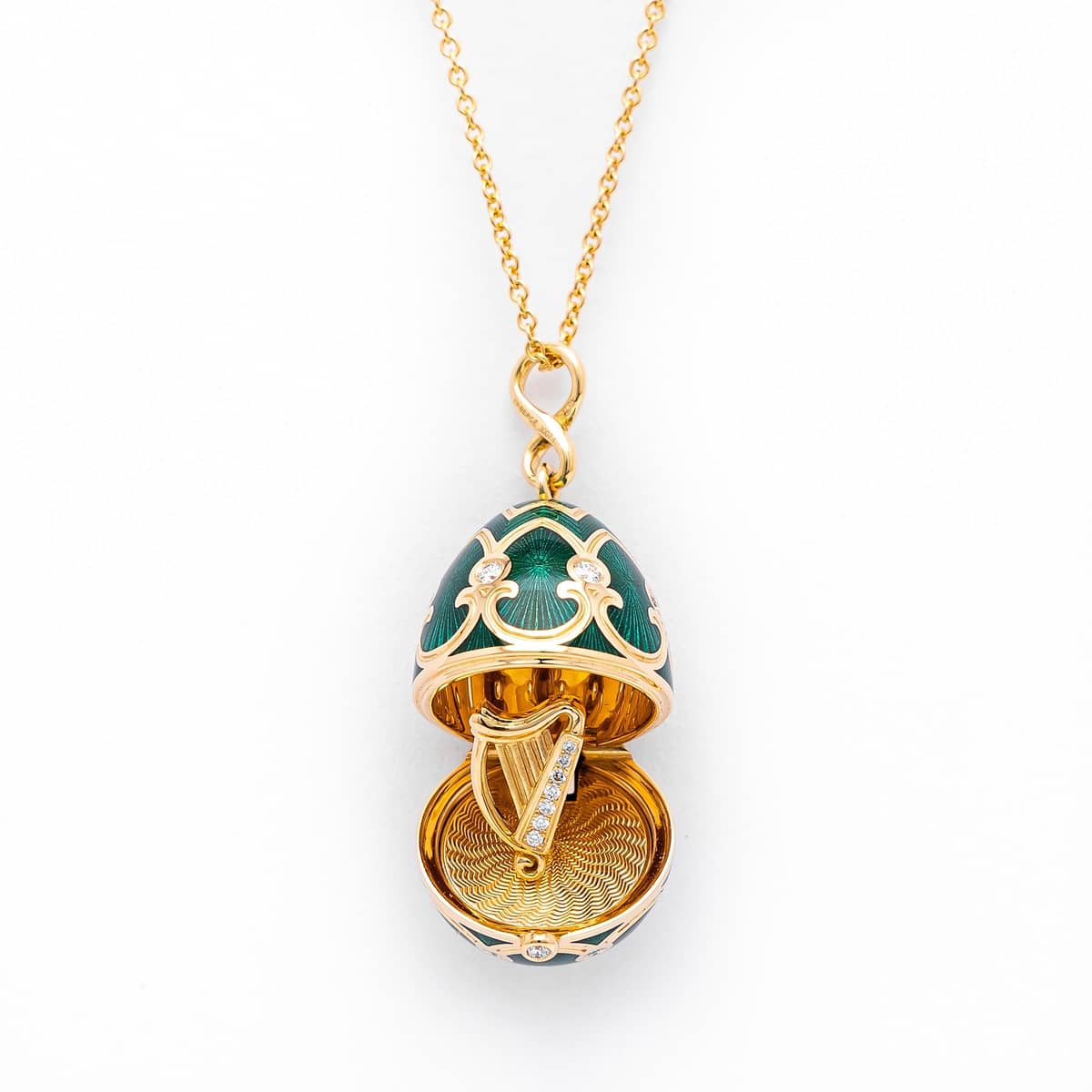 18k yellow gold Faberge Palais Tsarskoye Egg Harp Surprise locket.
The locket features a green guilloche ennamel egg decorated with diamonds. Concealed within the egg locket is a yellow gold harp set with round brilliant cut diamonds. The locket is suspended from an 18k yellow gold chain.
Total diamond carat weight: 0.30ct